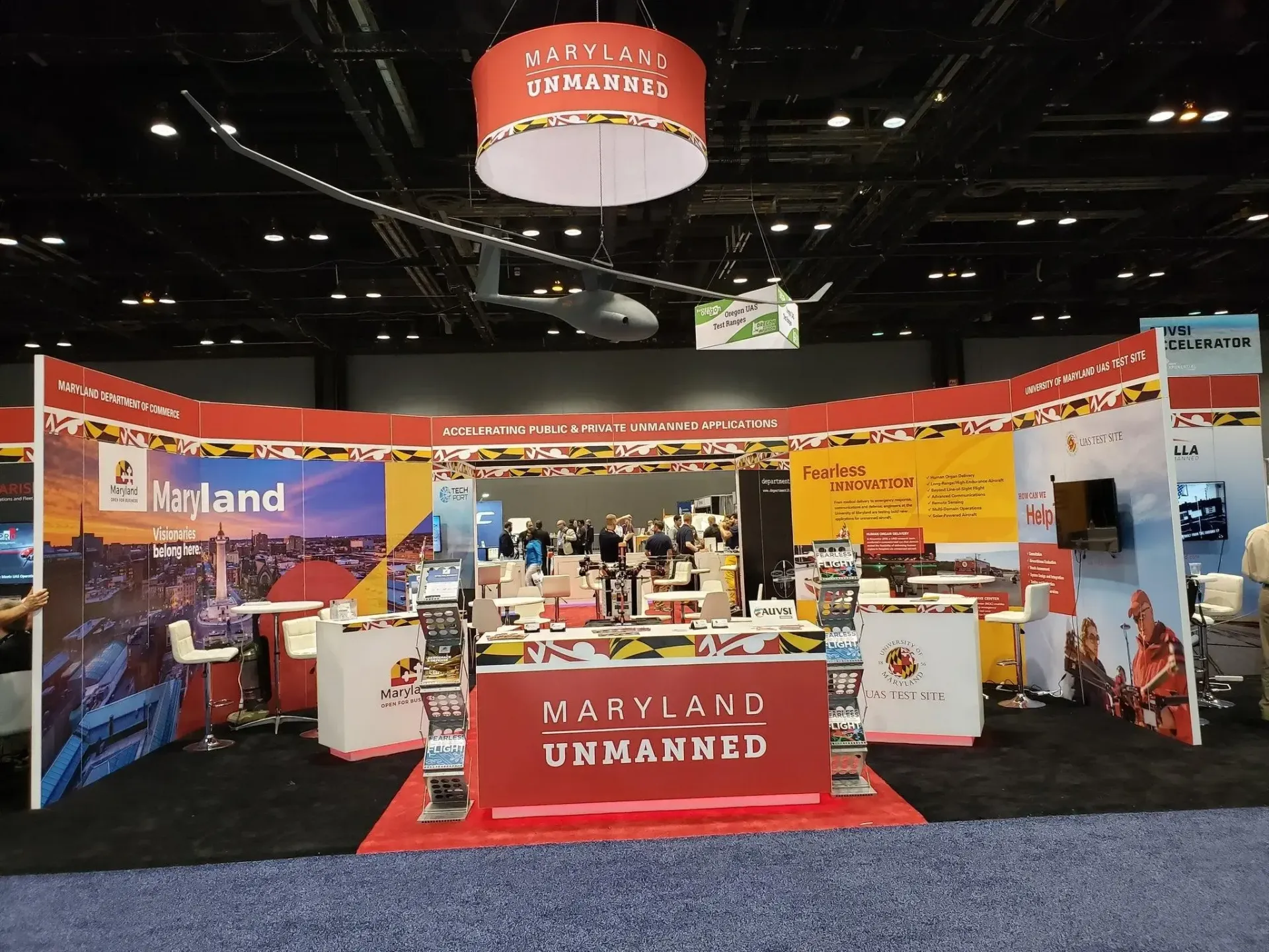 A conference booth with a red sign on the ground and hanging above that both read "Maryland Unmanned"