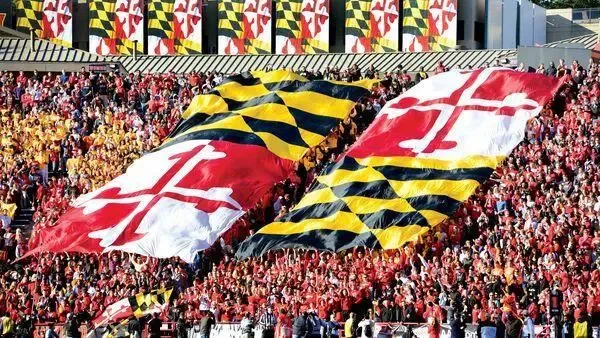 University of Maryland Football Fans in the stadium holding up large Maryland flags