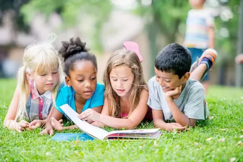 4 Children Lying in Grass Reading Book